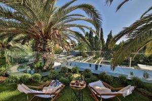 a resort with a palm tree and chairs and a pool at Hotel Park Split in Split