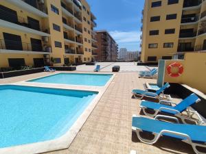 a swimming pool with lounge chairs next to some buildings at 4B Alto dos Navegantes - Casas & Papéis in Armação de Pêra