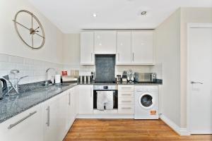 a kitchen with white cabinets and a washer and dryer at The Hidden Gem of Leeds with Parking - Sleeps 4 in Leeds
