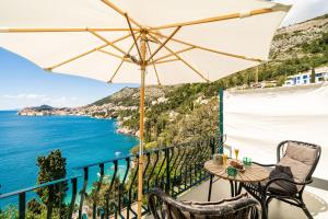 uma varanda com um guarda-sol e o oceano em Beach House Sveti Jakov 1 em Dubrovnik