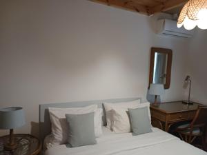 a bedroom with a bed with white pillows and a table at Theros & Trygos Boutique Houses - ATH Airport in Artemida