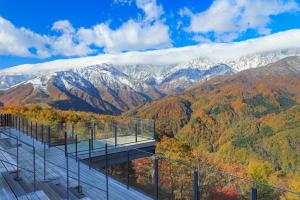 a glass building with mountains in the background at Tabist More Resort Nire no Ki Hakuba in Hakuba