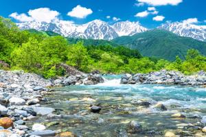 a river with rocks and mountains in the background at Tabist More Resort Nire no Ki Hakuba in Hakuba