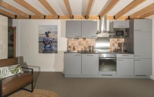 a kitchen with white cabinets and a couch in a room at Bed & Breakfast Zeeuws Gelukkig in Serooskerke