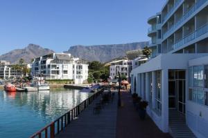 a dock with a marina with buildings and mountains at Spacious sea facing one bedroom apartment in Cape Town