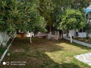 a yard with a table and chairs under trees at Muses apartments Eretria in Eretria