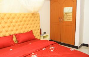 1 dormitorio con 1 cama con colcha roja en Artistic Oasis 2Bedrm Apartment, en Buwate
