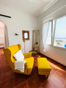 a living room with a yellow chair and a stool at Casa Pura Vida y el Mar in Caleta de Caballo