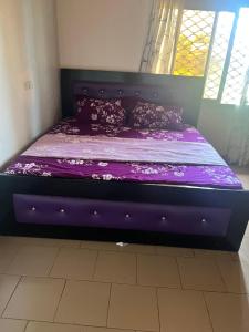 uma cama roxa num quarto com uma janela em A&G Guest House Kumba em Kumba