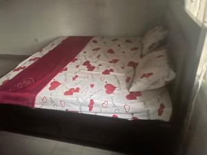 ein kleines Bett mit einem Laken mit Herz drauf in der Unterkunft A&G Guest House Kumba in Kumba