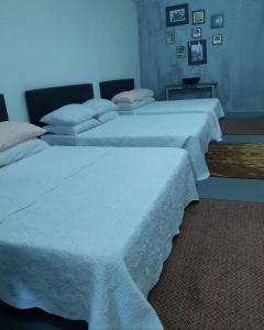 two beds in a room with white sheets at ROOMMATE STUDIO in Kuah