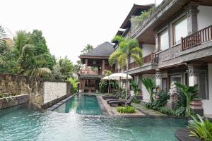 a swimming pool in front of a house at Budhi Ayu Villas and Cottages Ubud by Mahaputra in Ubud