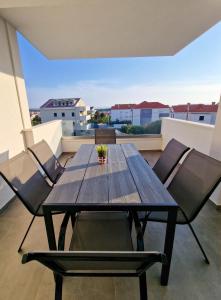 un tavolo e sedie di legno su un balcone di Villa Poseidon a Novalja (Novaglia)