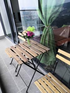 un banco de madera con un jarrón de flores sobre una mesa en Condo with great view in PJ en Petaling Jaya