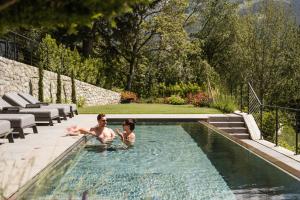 two people are sitting in a swimming pool at Private Suites COLLIS - Feel good Resort Johannis in Tirolo
