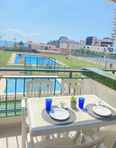 una mesa con platos y vistas a la piscina en NUEVO !!! Apartamento Peñíscola Playa con piscinas y tenis, en Peñíscola
