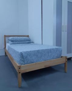 uma cama de madeira num quarto com fundo azul em ROOMMATE STUDIO em Kuah