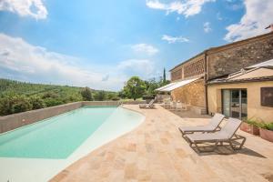 a swimming pool with two lounge chairs next to a building at Brotes Appartamento Castagno in Sovicille