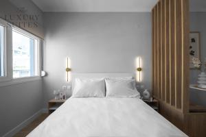 a white bedroom with a large bed with white pillows at Nephele, The Luxury Suites in Thessaloniki