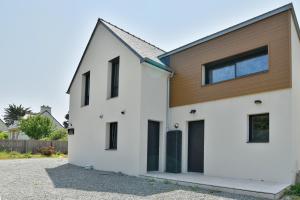una casa blanca con ventanas negras y una pared de madera en Duplex Gwenan - Maisonnette proche plage, en Saint-Cast-le-Guildo