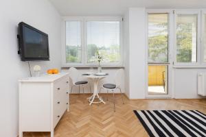 a white dining room with a table and a tv at Studio with Balcony 300m to the Beach Sopot by Renters in Sopot