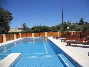 ein großes Schwimmbecken mit Holzbänken und sidx sidx sidx in der Unterkunft Hotel Foxes in Villa del Dique