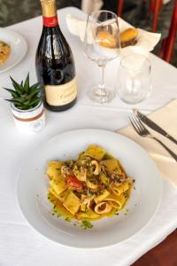een bord pasta op een tafel met een fles wijn bij Hotel Plaza in Cattolica