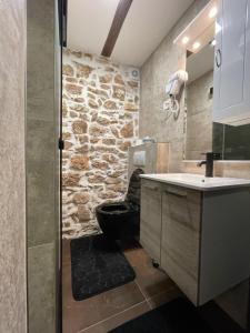 La salle de bains est pourvue d'un mur en pierre, de toilettes et d'un lavabo. dans l'établissement Tequila Apartments, à Zadar
