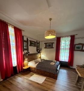a bedroom with a bed with red curtains and a chandelier at Rooms Murka in Bled
