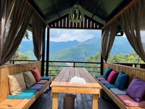 HualingにあるLala Mountain Homestay‧Cile Farmの山を背景にしたデッキのテーブルとベンチ