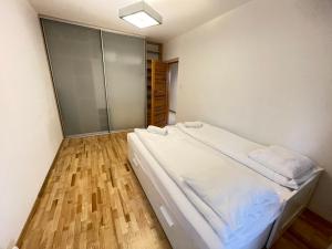 um quarto com uma cama branca e piso em madeira em Apartament Park Zakrzowek em Cracóvia