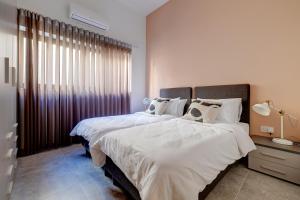 een slaapkamer met 2 bedden met witte lakens en een raam bij Modern 3BR Apartment in Sliema's Desirable Locale in Sliema +40 foto's