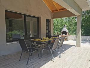 a patio with a table and chairs and a fireplace at Kuća za odmor -FourM in Novak