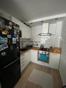 a kitchen with white cabinets and a black refrigerator at Dwa pokoje w centrum - darmowy parking in Świnoujście
