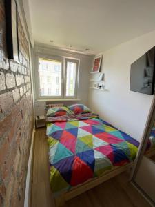 a bedroom with a colorful bed and a brick wall at Dwa pokoje w centrum - darmowy parking in Świnoujście