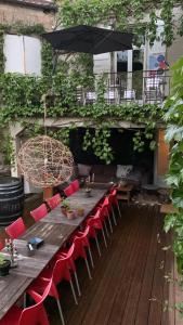 a long wooden table with red chairs and an umbrella at " Venez DormiR Chez Nous " #Condom#Gascogne#d'Artagnan#Armagnac#Le Bonheur est dans le GERS in Condom