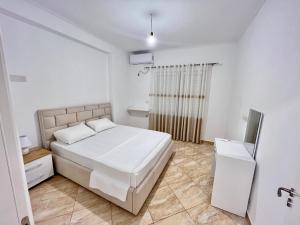 una camera bianca con letto e televisore di Gregor Apartments 1 a Sarandë