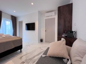 a bedroom with a bed and a tv on a wall at Azalea Dalmacija Luxury Rooms and Apartments in Primošten