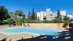 ein Pool mit Stühlen und ein Gebäude im Hintergrund in der Unterkunft Mar by Check-in Portugal in Albufeira