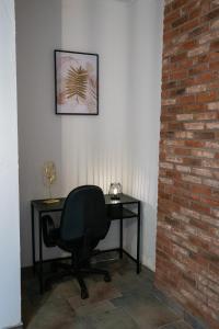 een zwart bureau met een stoel naast een bakstenen muur bij Le Studio Baltard in Charleroi