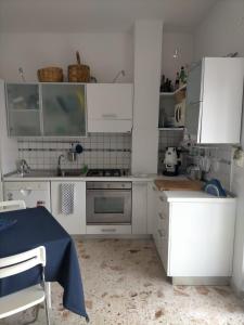 cocina con armarios blancos y fogones en Notti sul mare a Villa Chiara en Marina di Casalvelino
