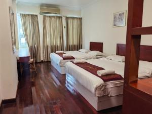 2 łóżka w pokoju z drewnianymi podłogami i oknami w obiekcie SC Hotel Melaka w Malakce