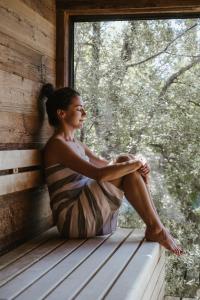 Eine Frau, die auf einer Fensterscheibe sitzt und rausschaut. in der Unterkunft Feel good Resort Johannis in Dorf Tirol