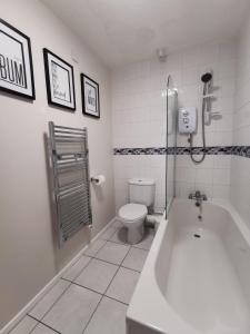 a bathroom with a bath tub and a toilet at Apartment by the Beach in Swansea
