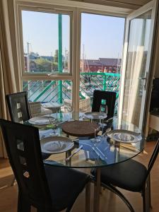 a dining room table with chairs and a view of a boat at Apartment by the Beach in Swansea