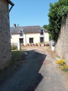 una casa bianca con un muro di pietra accanto a una strada di La longère a Épineu-le-Chevreuil