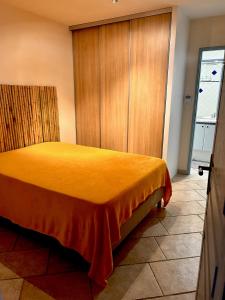 a bedroom with a yellow bed with a wooden closet at Dans Baptiste traditionnellle appartement de la plage et terrasse Balli in Rayol-Canadel-sur-Mer