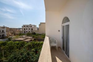 a white building with a chair on a balcony at Spacious Luxury 3BR Apartment with Terrace & Open Views - Zurrieq, close to sea in Żurrieq