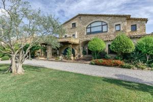 a stone house with a tree in the yard at La Masía Grande de Can Gat Vell in Llampaies