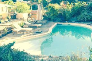 a swimming pool with an umbrella and chairs in a yard at Villa Roquefortoise avec piscine in Roquefort-les-Pins
